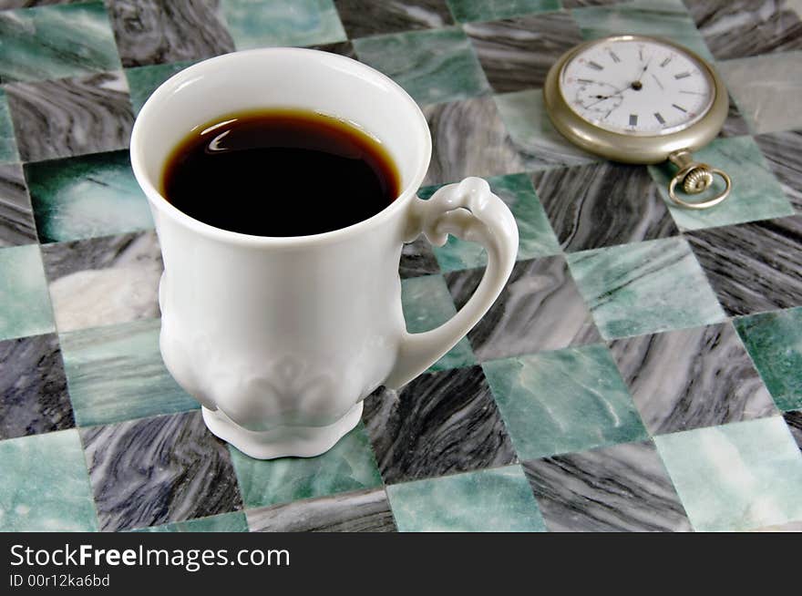 Cup of coffee with an antique pocket watch in the background. Cup of coffee with an antique pocket watch in the background.