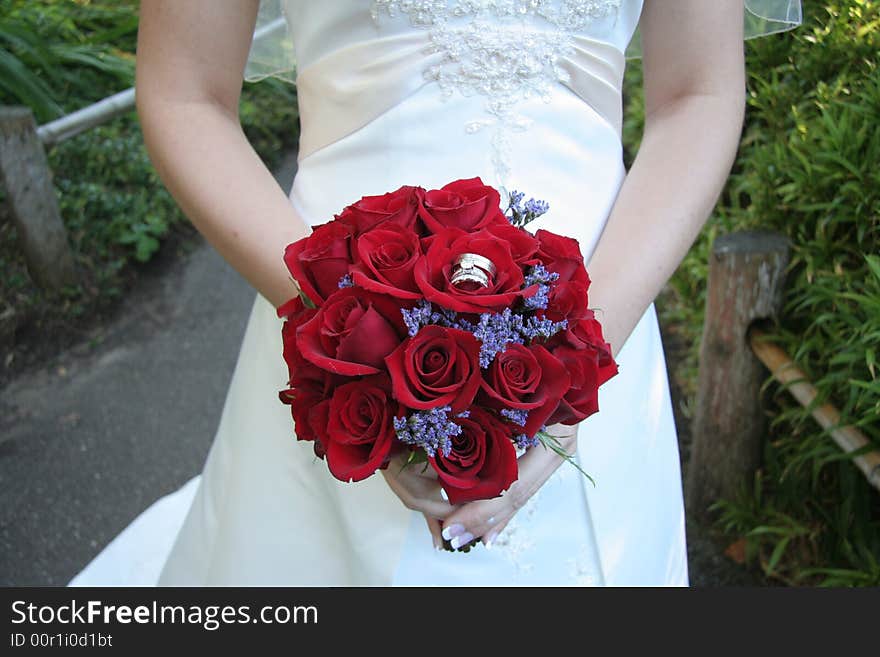 Bride holds her bouquet of red roses. Focus on flowers. Bride holds her bouquet of red roses. Focus on flowers.