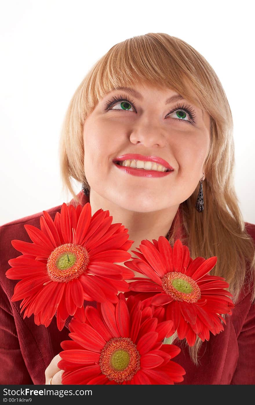 A smiling girl with red flowers looking up