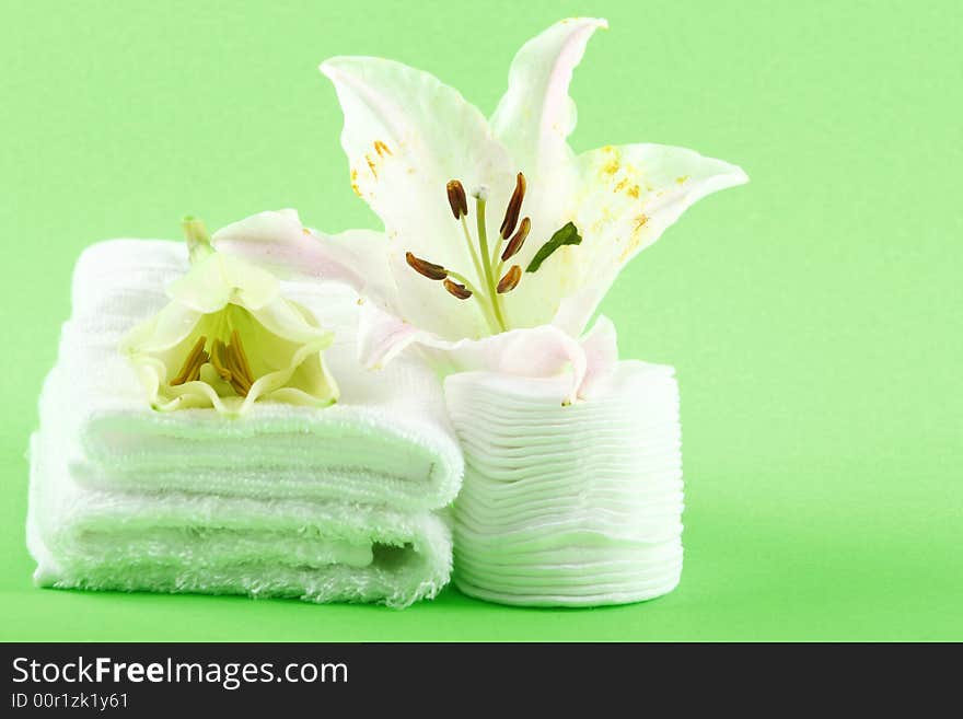 white towels and fresh lily on green color background