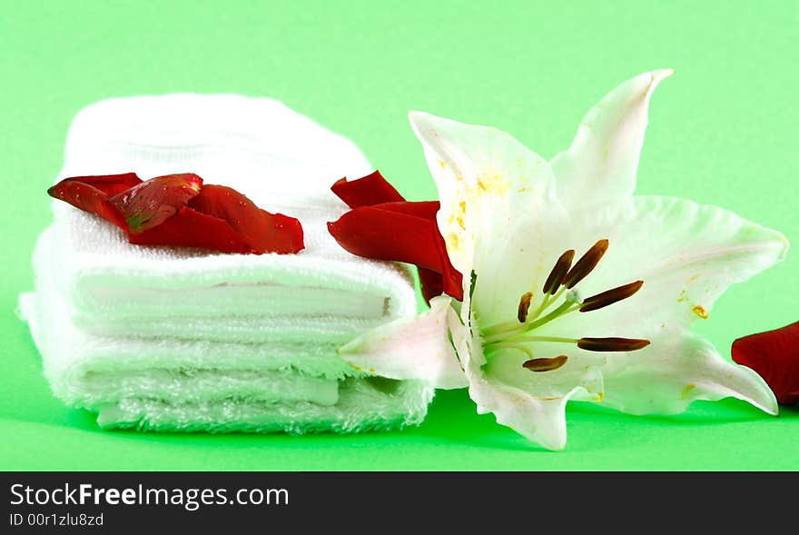 white towels and fresh lily on green color background