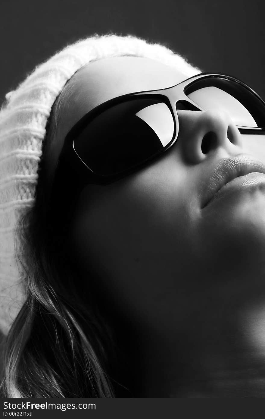 Portrait of a beautiful woman with a cap and some sunglasses against grey background. Portrait of a beautiful woman with a cap and some sunglasses against grey background