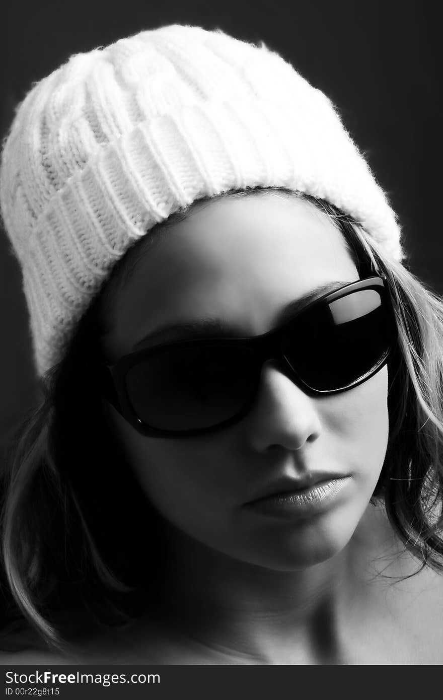 Portrait of a beautiful woman with a cap and some sunglasses against grey background. Portrait of a beautiful woman with a cap and some sunglasses against grey background