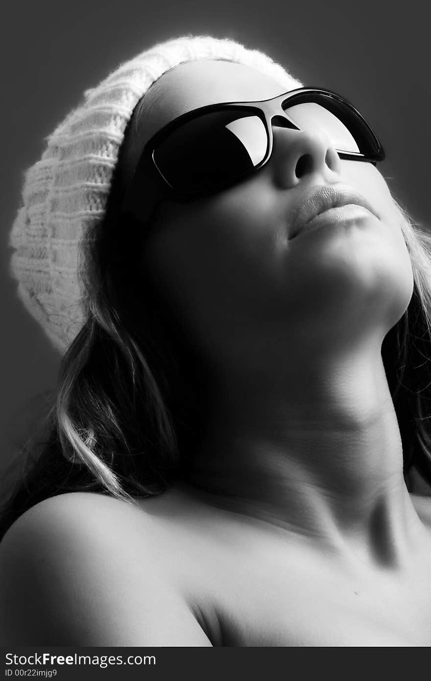 Portrait of a beautiful woman with a cap and some sunglasses against grey background. Portrait of a beautiful woman with a cap and some sunglasses against grey background