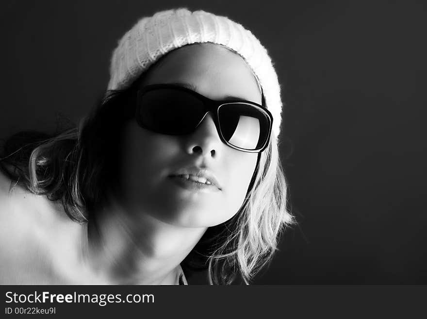 Portrait of a beautiful woman with a cap and some sunglasses against grey background. Portrait of a beautiful woman with a cap and some sunglasses against grey background