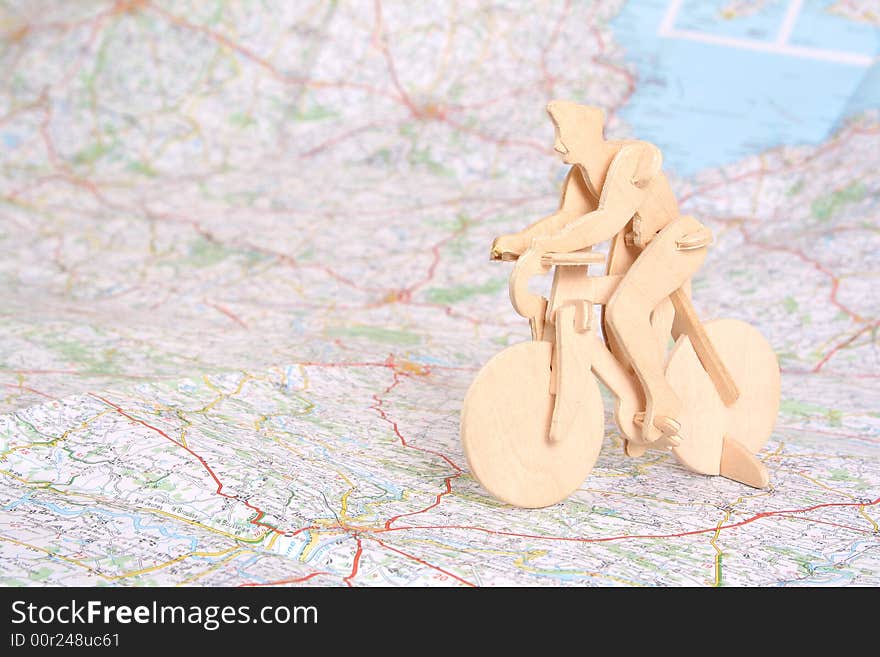 Wooden model of bicyclist on background of map. Wooden model of bicyclist on background of map