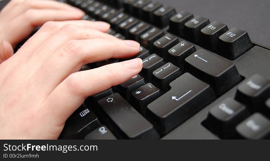 Pair of hands typing on a black keyboard. Pair of hands typing on a black keyboard