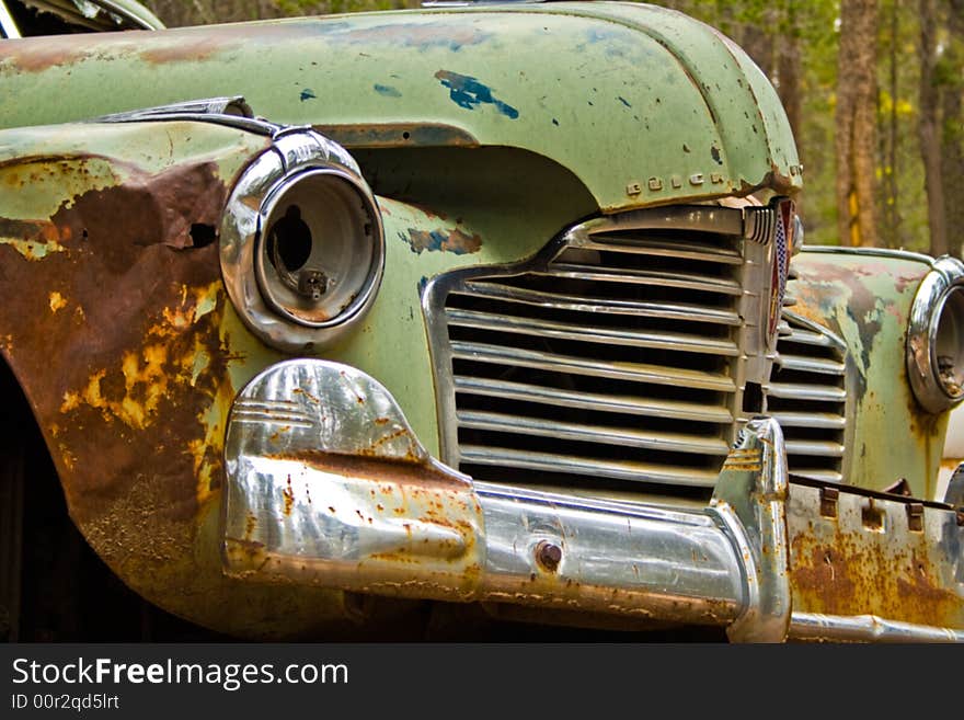 The front view of a green Buick  hardtop abandoned in the woods. The front view of a green Buick  hardtop abandoned in the woods