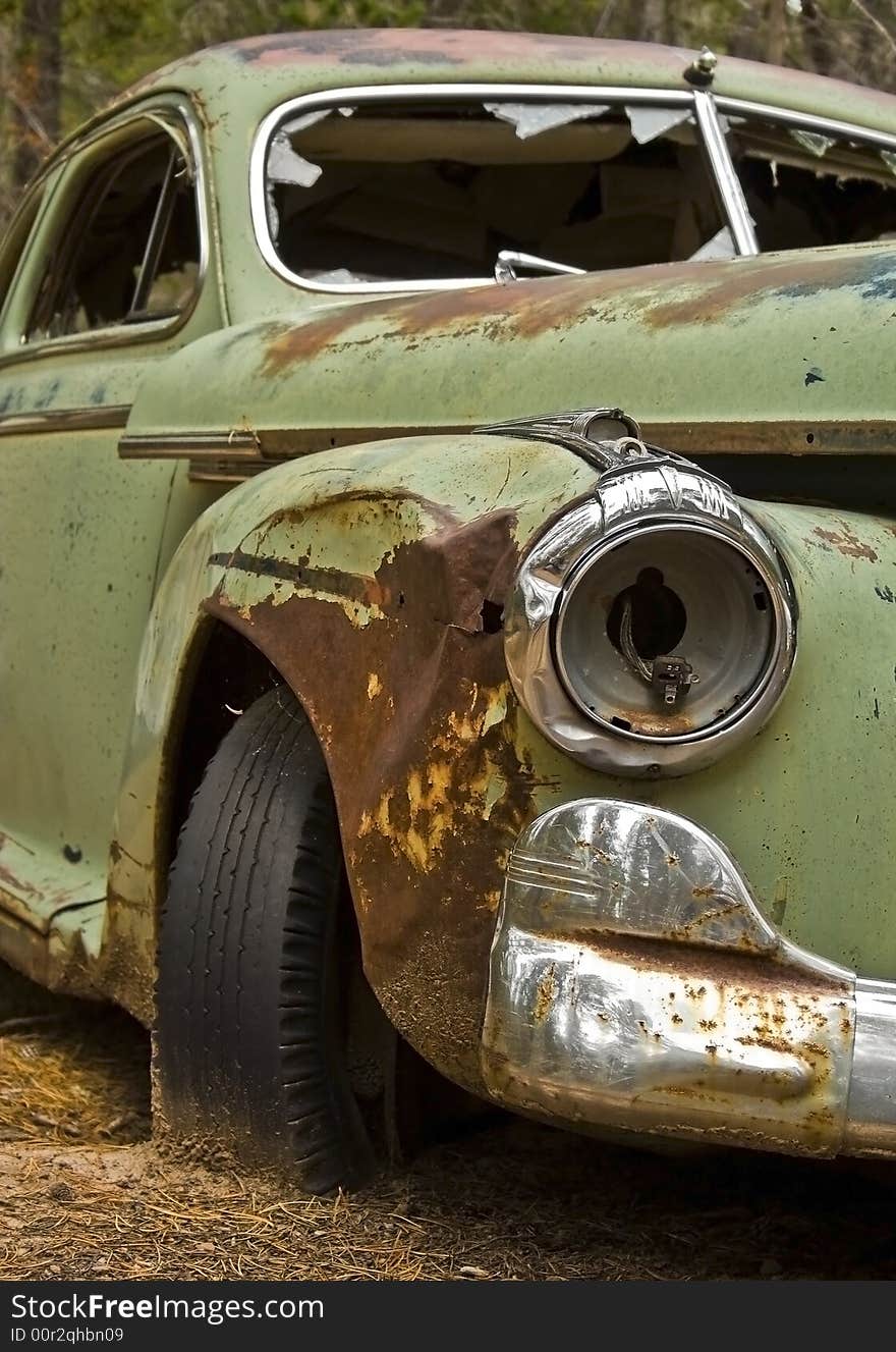 The front view of a green Buick hardtop abandoned in the woods. The front view of a green Buick hardtop abandoned in the woods