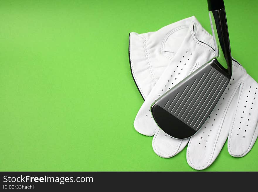 Golf glove and club on a green background