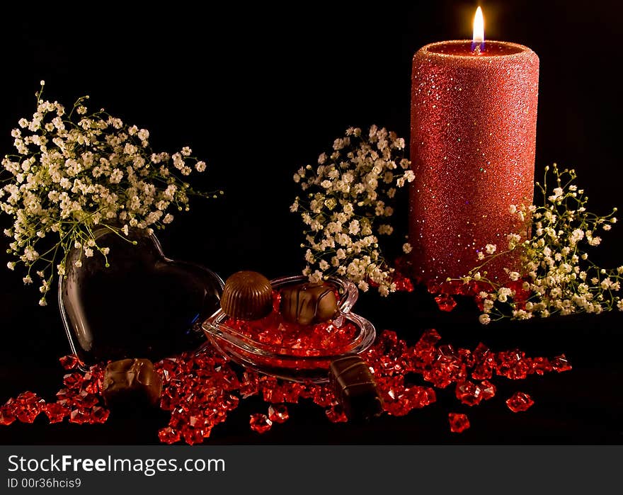 A red rose bud on a black background with red beads lying around. A red rose bud on a black background with red beads lying around