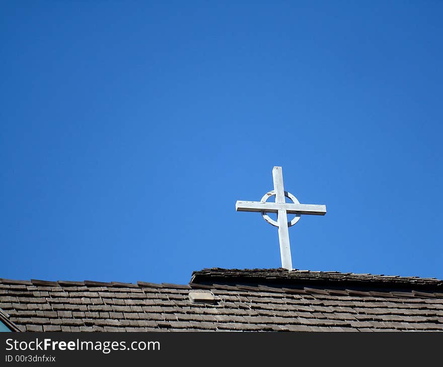 Cross on church roof with blue sky behind.