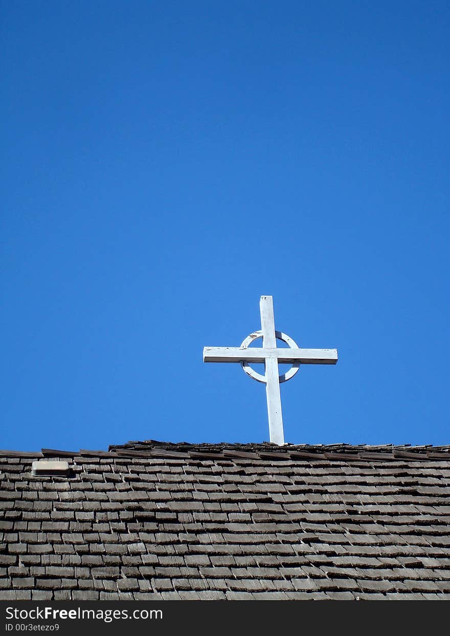 Cross on church roof with blue sky behind.