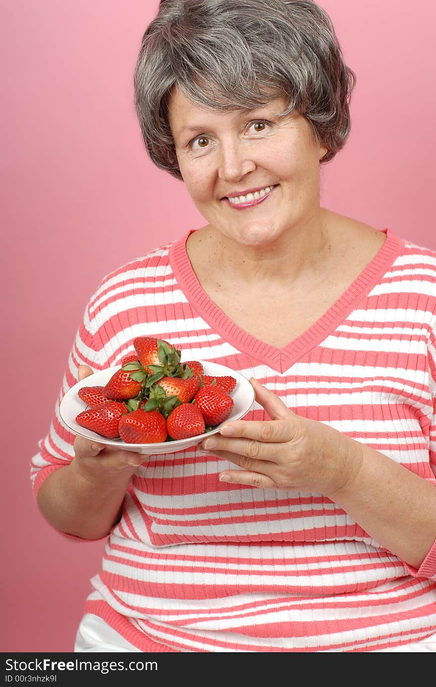 Portrait of a healthy senior woman with a bowl of strawberries. Portrait of a healthy senior woman with a bowl of strawberries