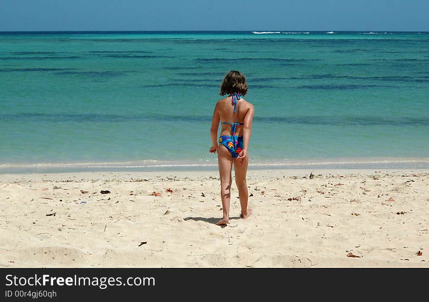 Girl walking to the sea on a tropical beach