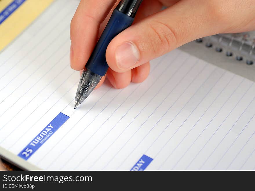 Close up of a hand writing in a daily planner