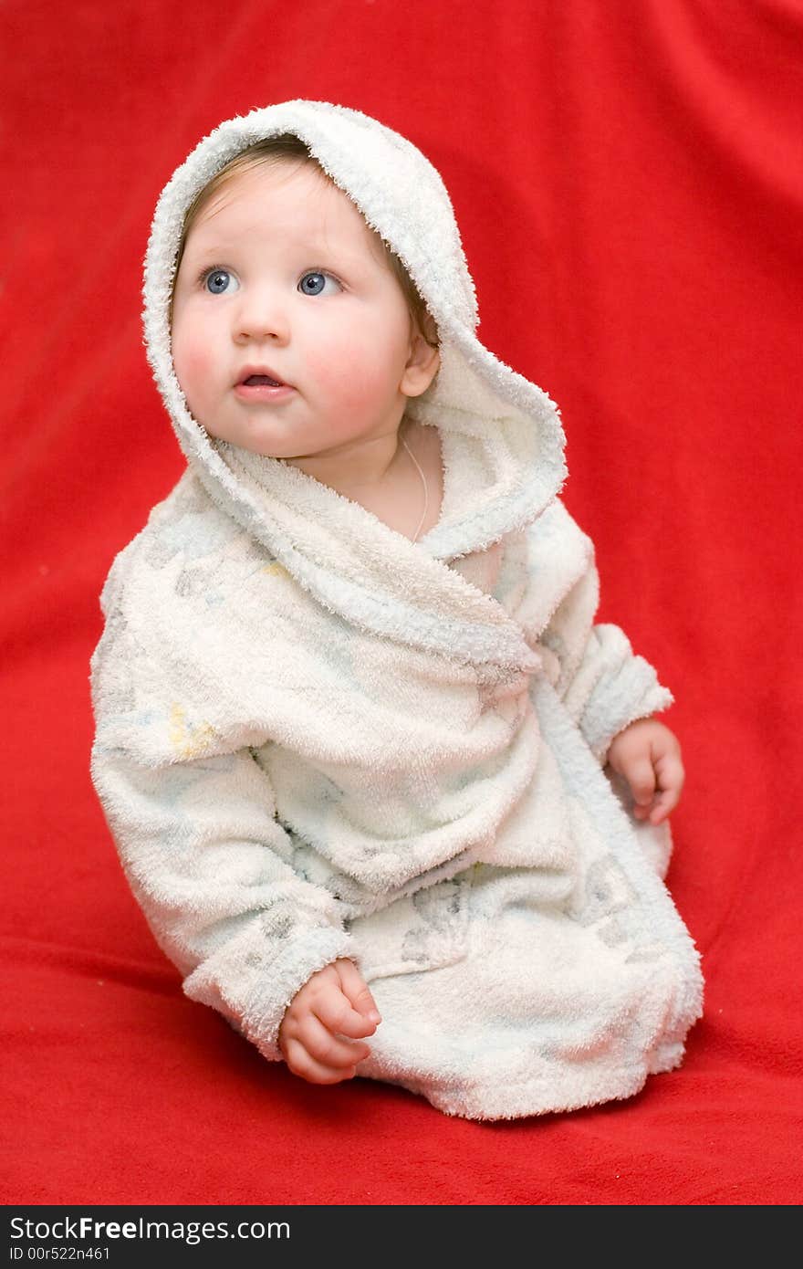 Baby in a white dressing-gown on a red background