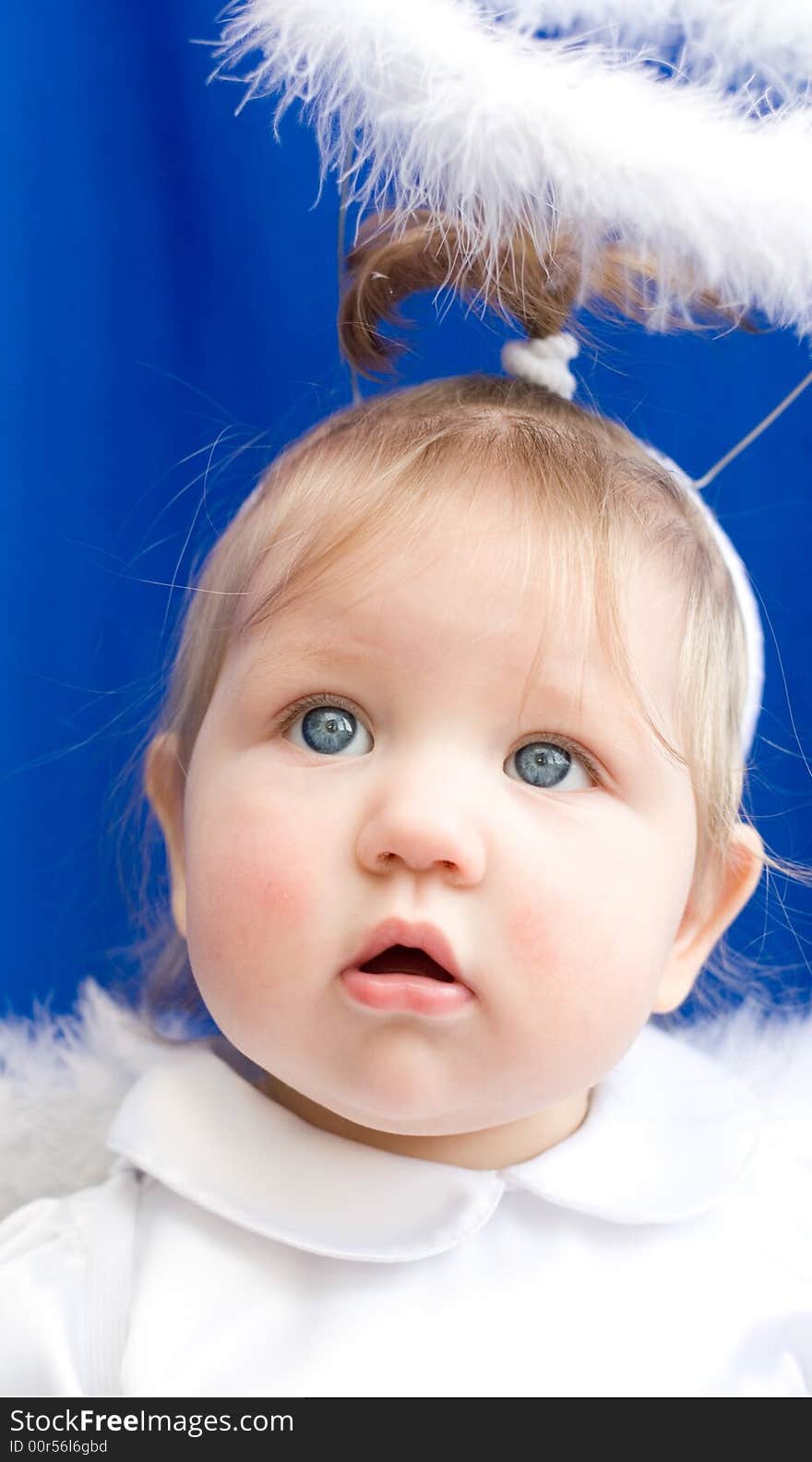 Portrait of Girl of angel in white clothes and with a nimbus on a dark blue background