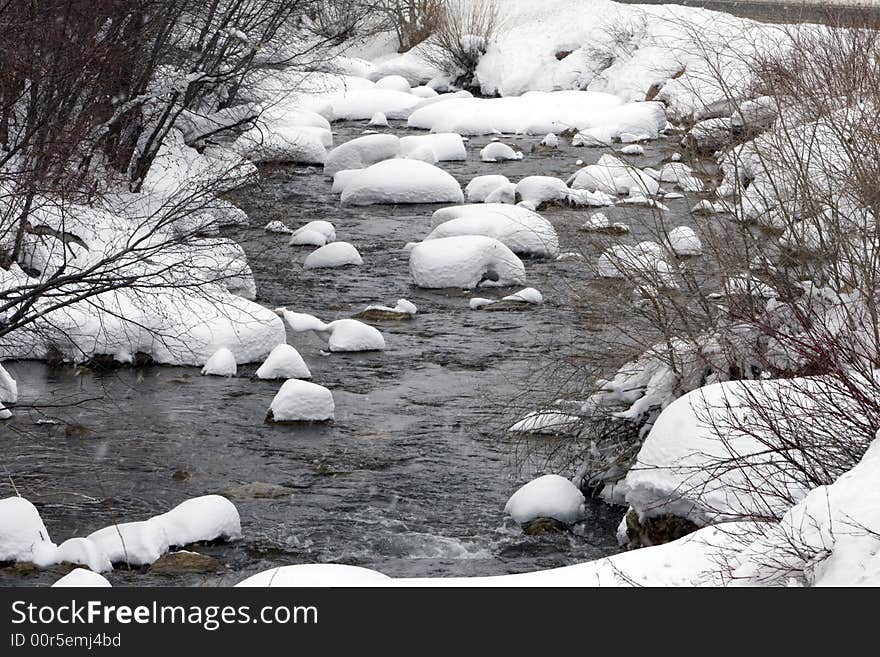 Snow-covered rocks in a river. Snow-covered rocks in a river.