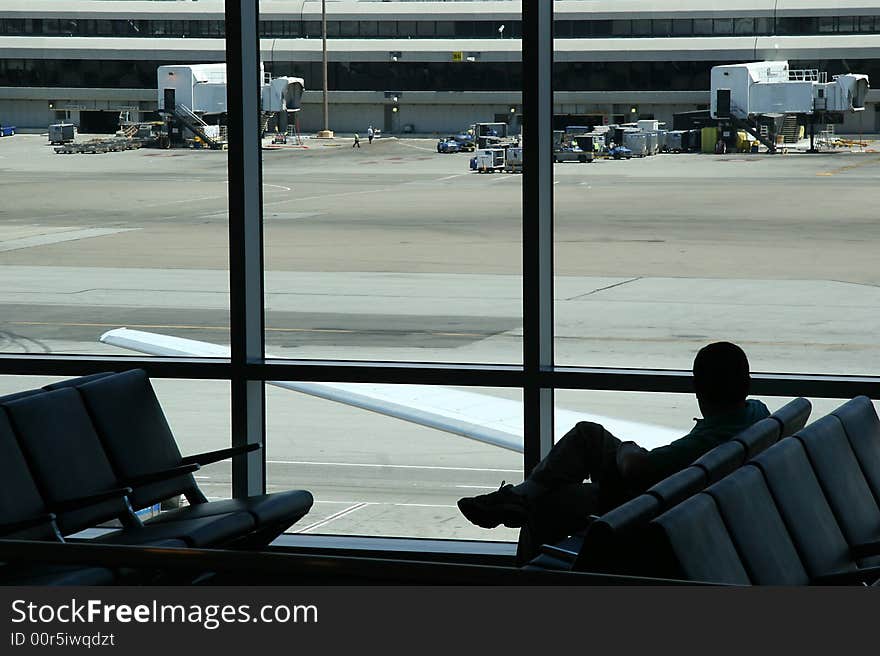 Silhouette of sitting man waiting at the airport, looking out at the runway. Silhouette of sitting man waiting at the airport, looking out at the runway.