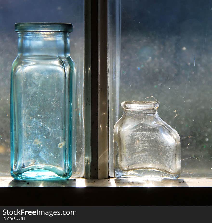 Two old medicine bottles lit by the sun.