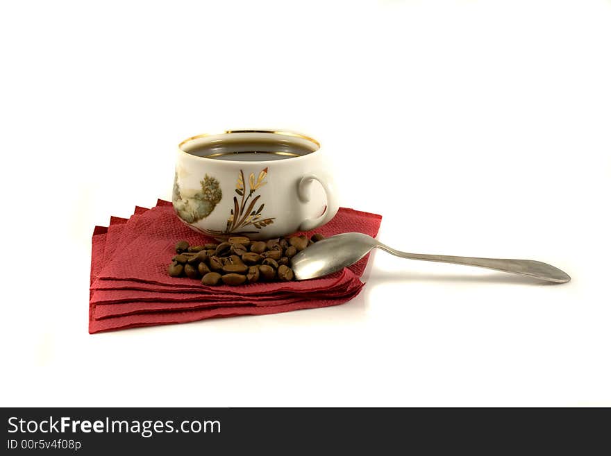 An isolated cup of hot coffee on a red napkin with some coffee-beans. An isolated cup of hot coffee on a red napkin with some coffee-beans