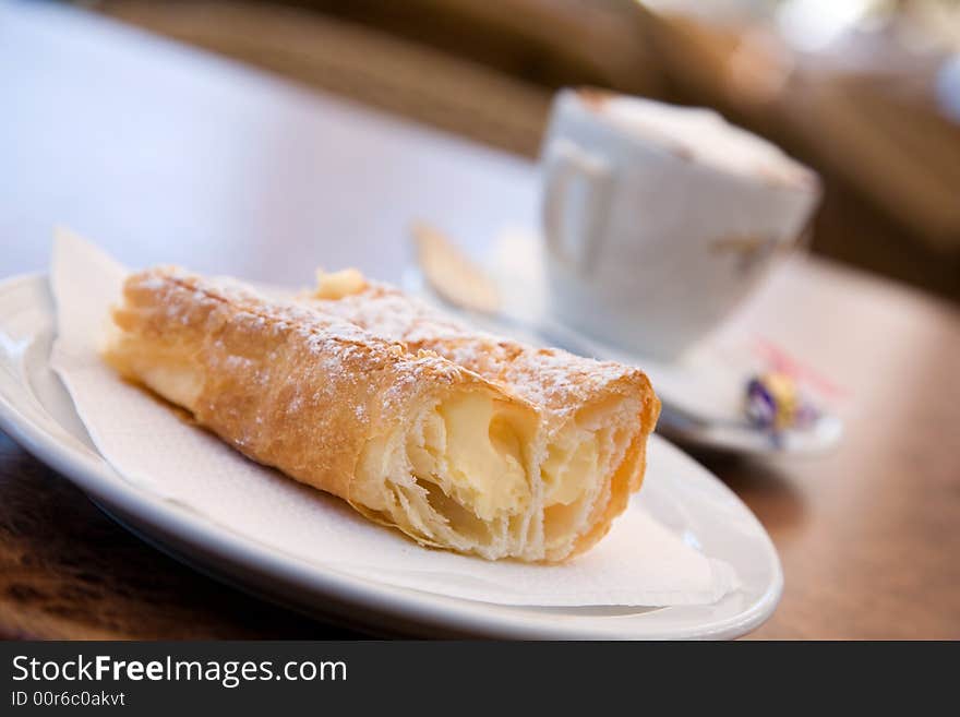 Cappuccino and delicious pastry on cafe table