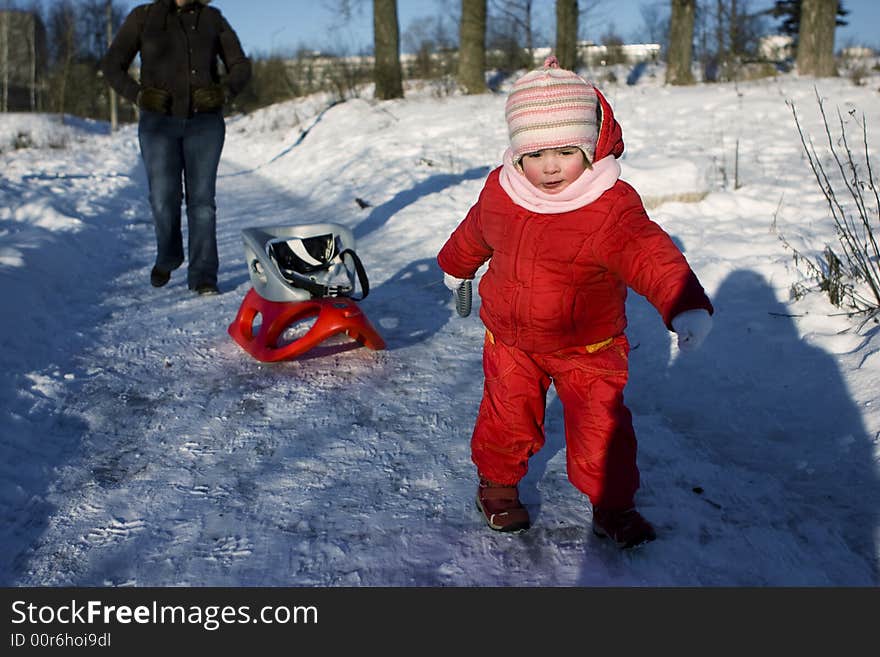 Young child dragging her sled in a winter park. Young child dragging her sled in a winter park.