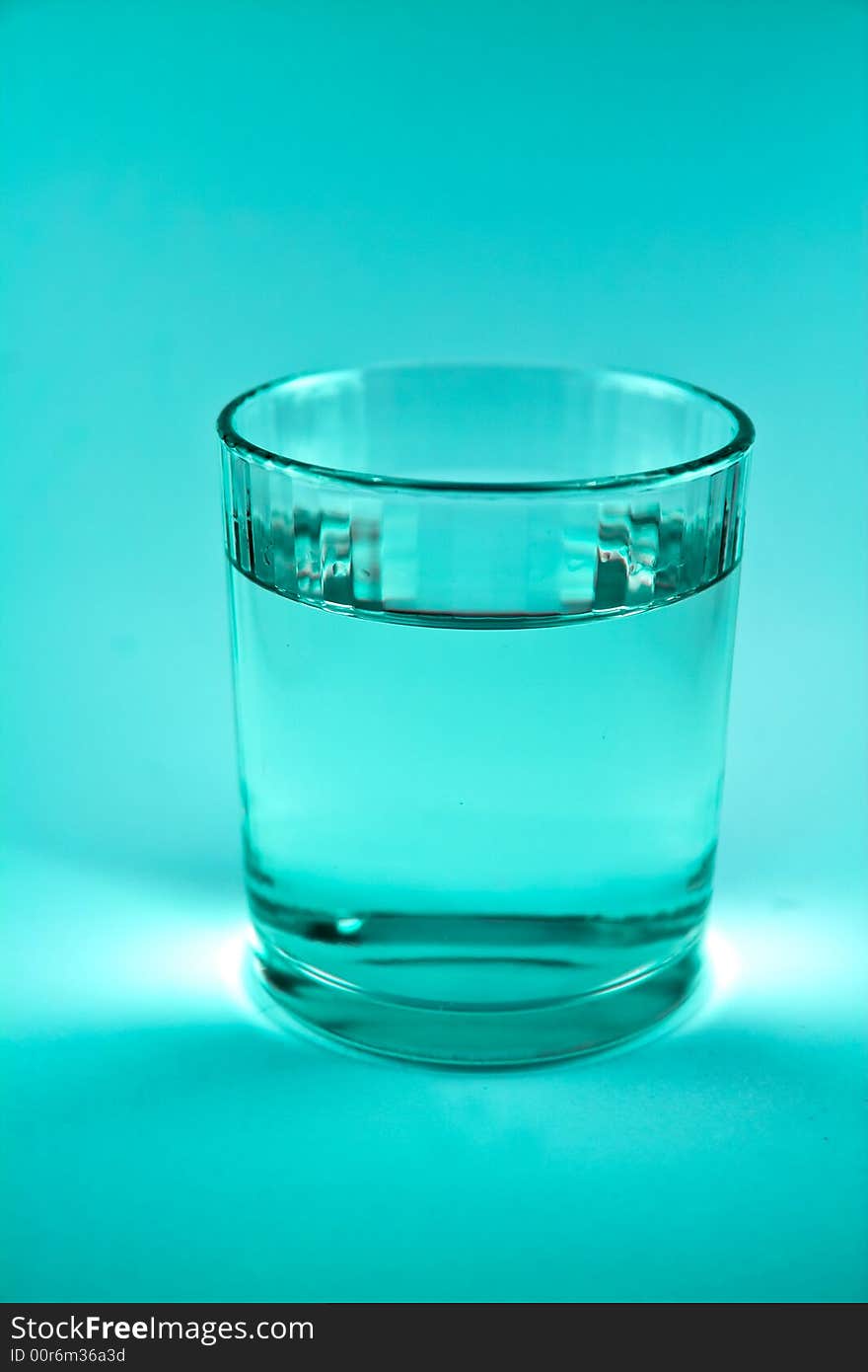 Single glass of water in blue-green colour macro