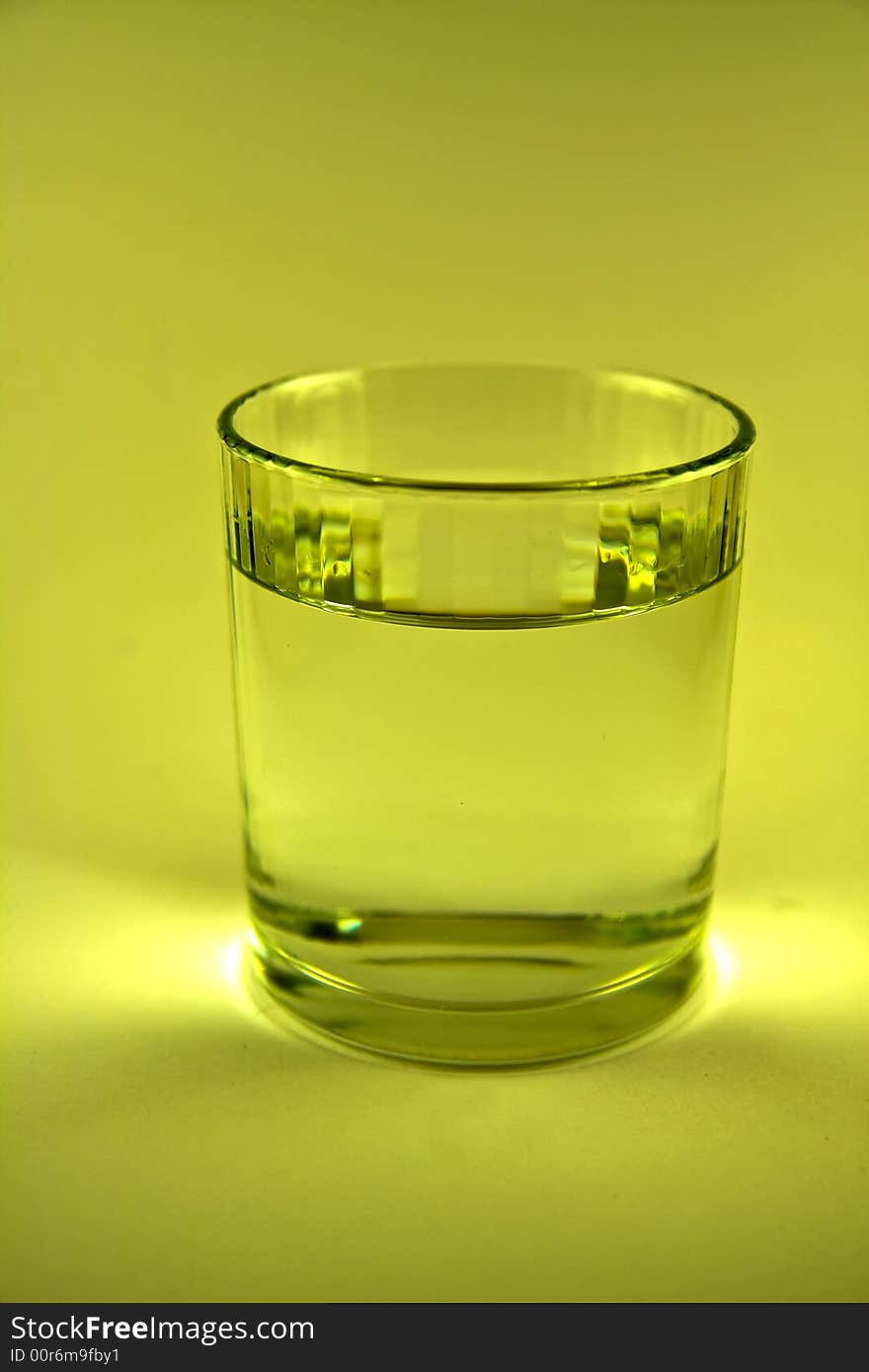 Single glass of water in yellow-green  colour macro