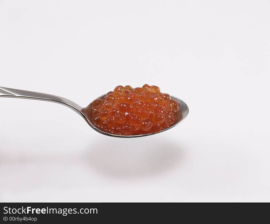 The spoon with red caviar on a white background