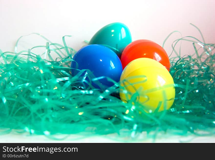 Yellow, blue, red and green plastic Easter Eggs in green plastic grass, isolated on white