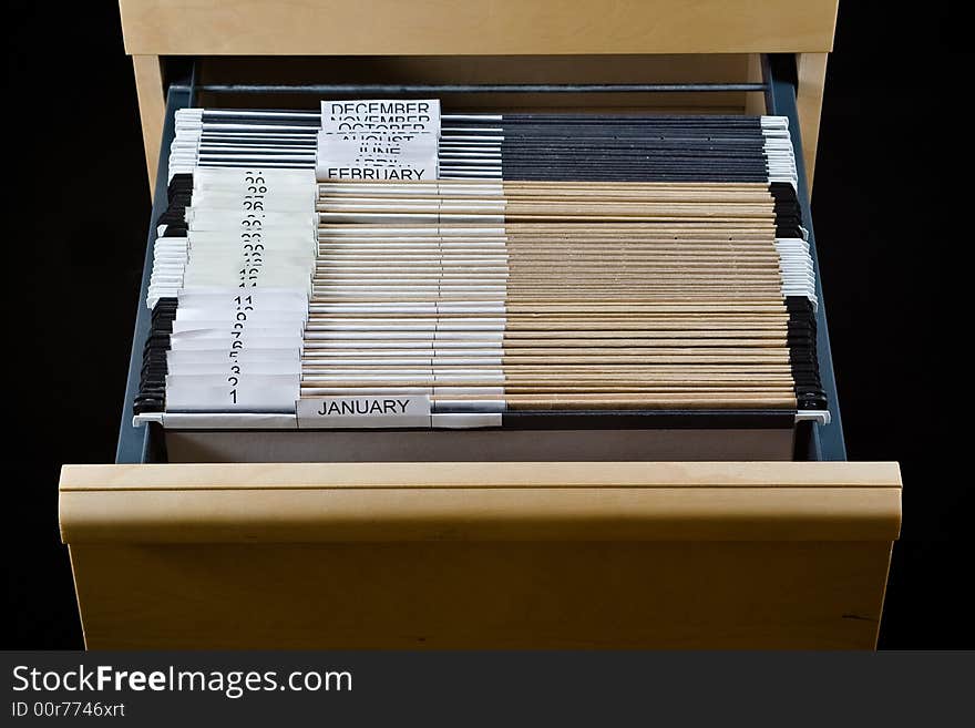 Wooden rolling file cabinet with a drawer opened, showing 43 hanging folders. Wooden rolling file cabinet with a drawer opened, showing 43 hanging folders.