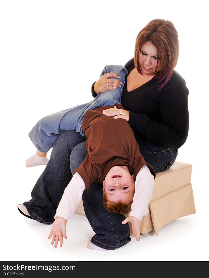 Preschool boy hanging upside down from his mom's lap. Isolated on white. Preschool boy hanging upside down from his mom's lap. Isolated on white.