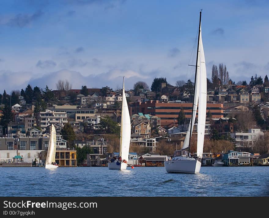 Three symmatrical yachts on a lake with city on background. Three symmatrical yachts on a lake with city on background