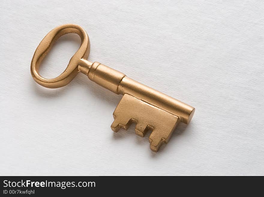 Brass key on textured white background