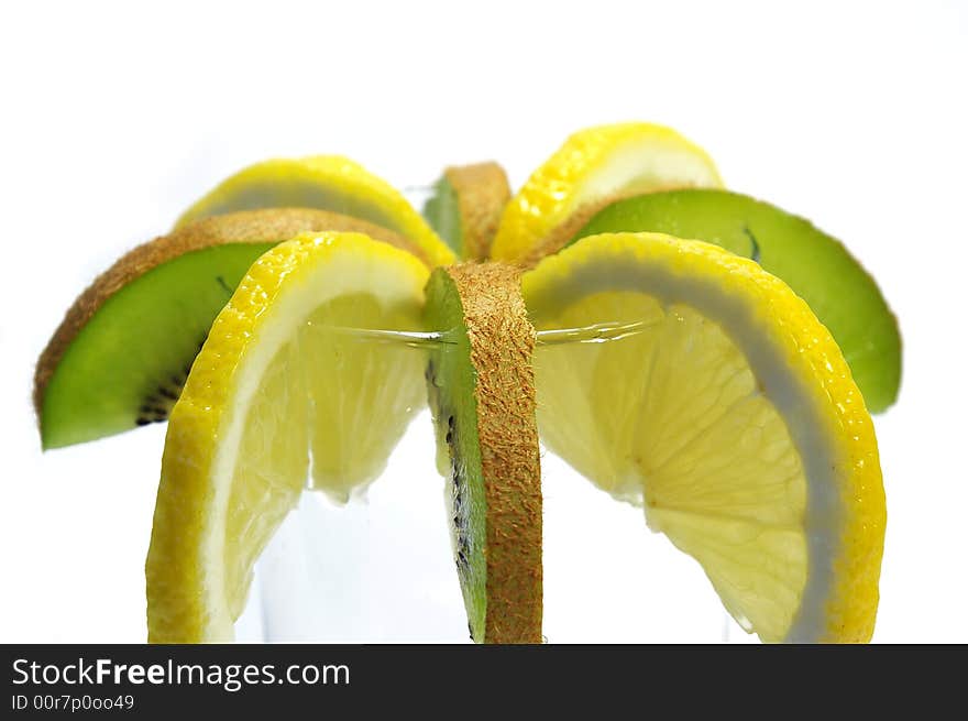 Parts of lemon and kiwi in the glass on white background. Parts of lemon and kiwi in the glass on white background