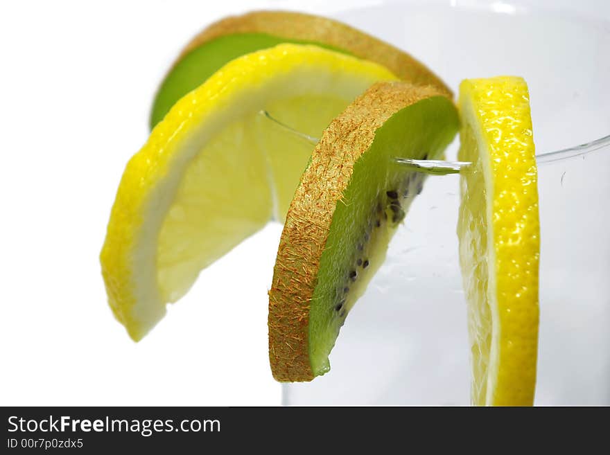 Parts of lemon and kiwi in the glass on white background. Parts of lemon and kiwi in the glass on white background