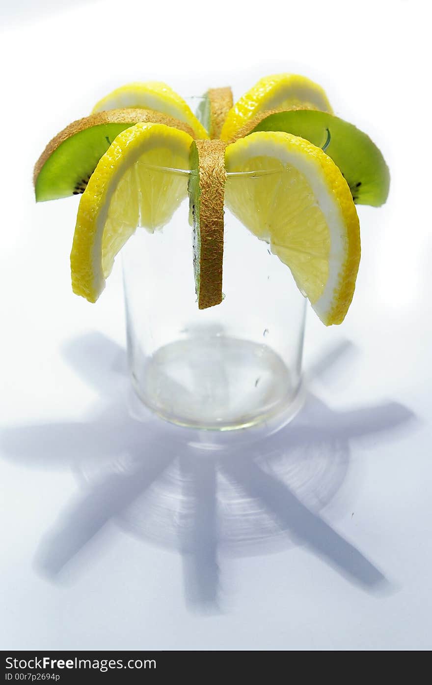 Parts of lemon and kiwi in the glass on white background