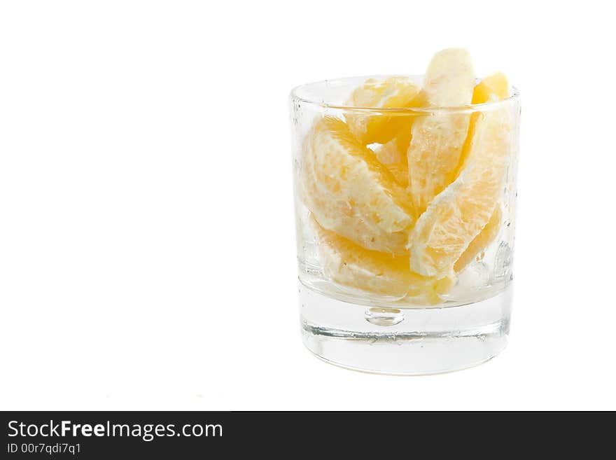 Lobules of orange in transparent glass isolated on white. Lobules of orange in transparent glass isolated on white