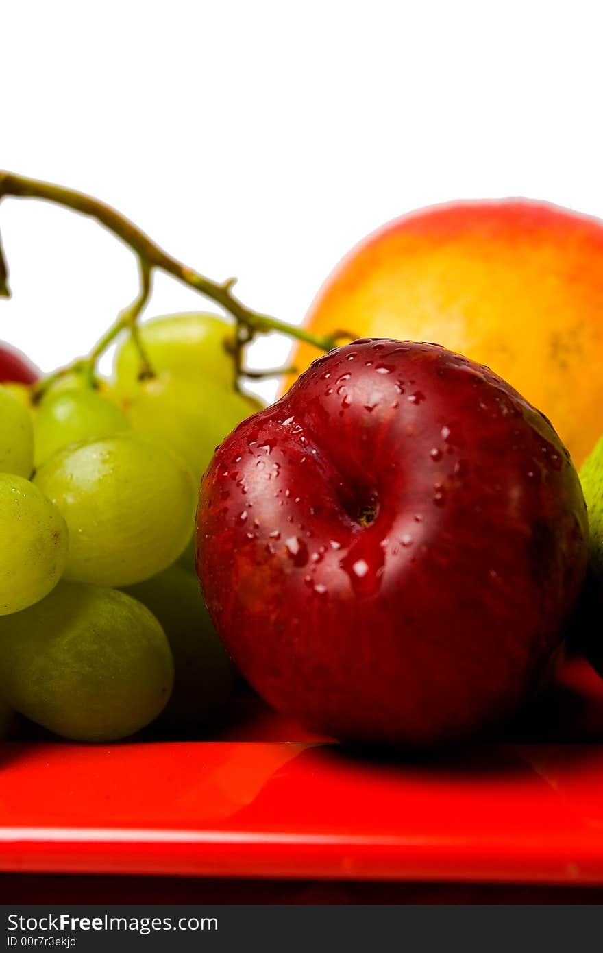 Assortment of fresh fruit arranged on a bright red serving dish. Assortment of fresh fruit arranged on a bright red serving dish.