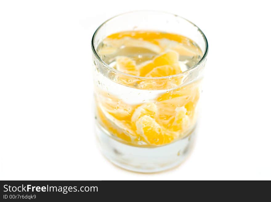 Lobules of mandarine at glass water isolated on white