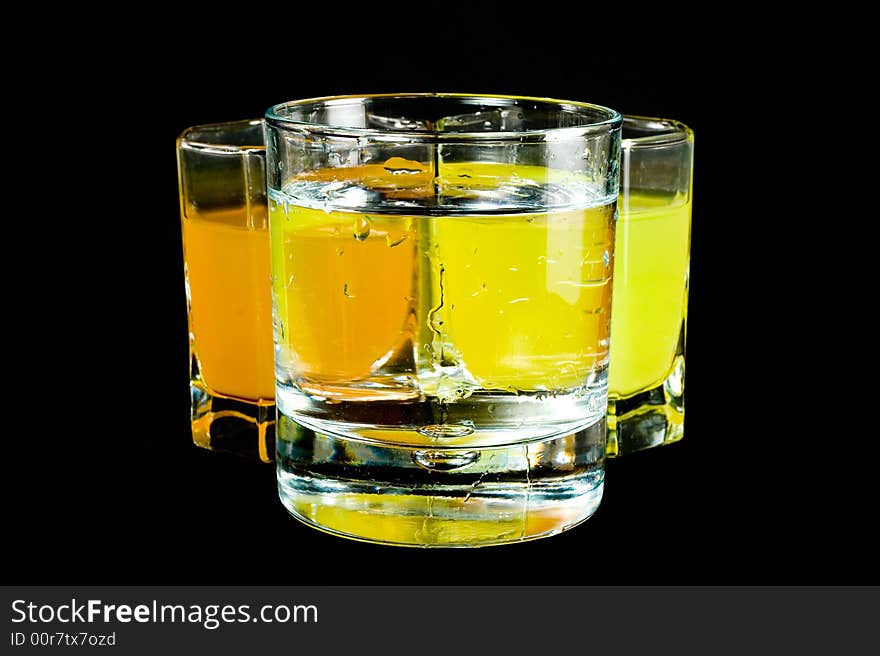 Three glasses with colored liquid isolated on black background