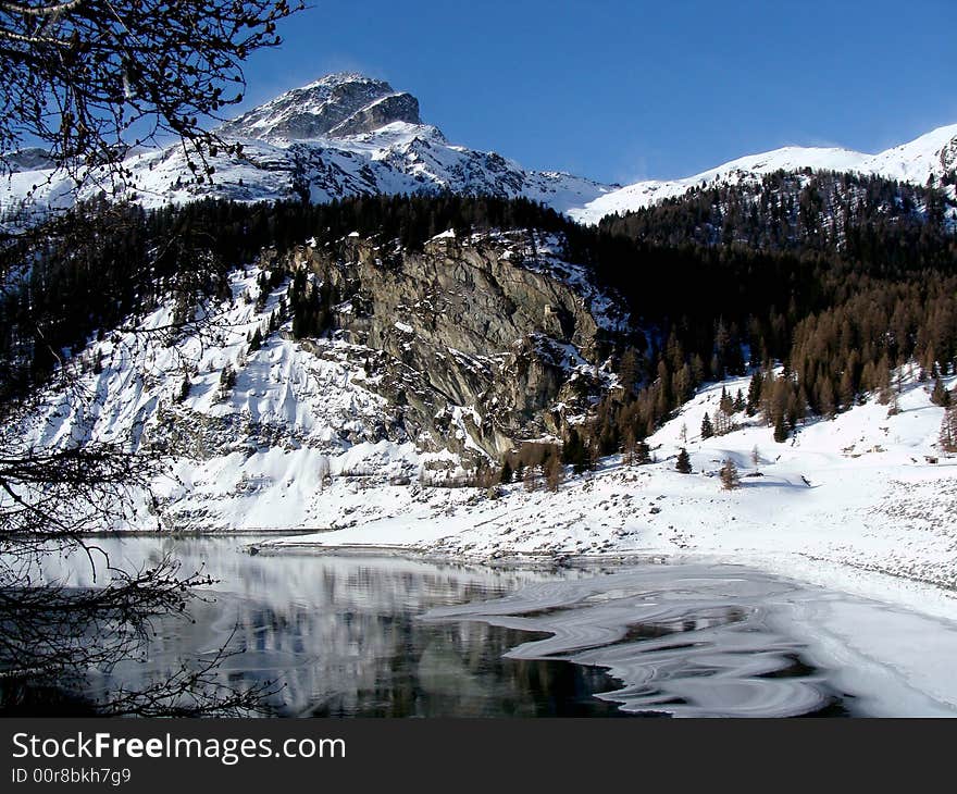 The partly frozen Marmorera Reservoir - besides the road to the Julier Pass - and Mount Piz Ela, 3339 m / 10955 ft., eastern Switzerland. The former village of Marmorera became a victim of the reservoir and then was built in a higher place.