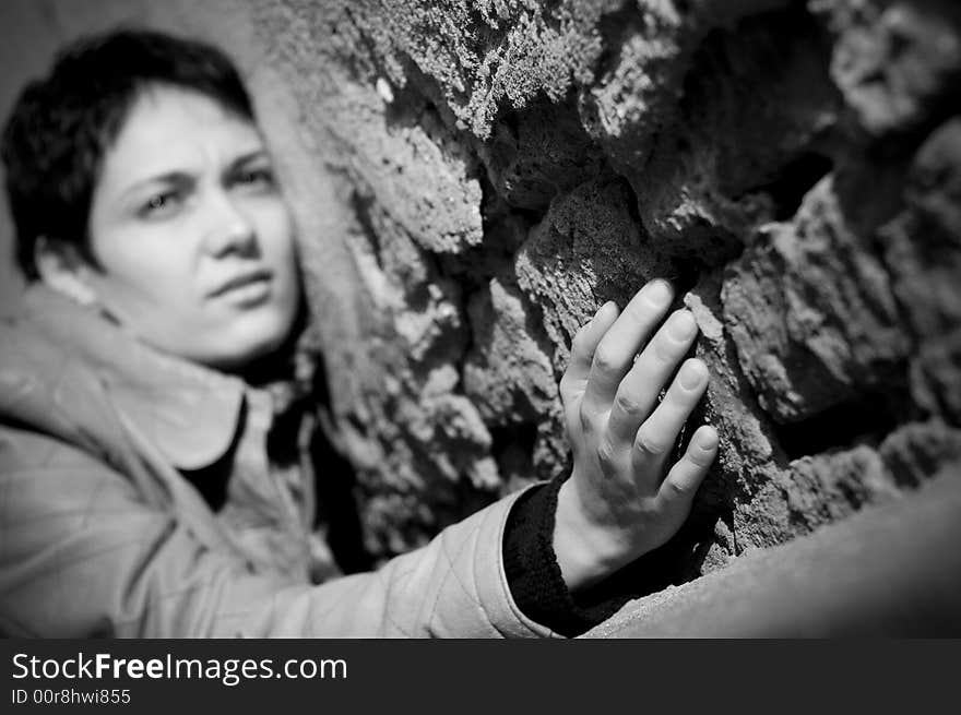 A view with a woman looking thoughtful in black and white tones. Shallow depth of field, focus on the hand.