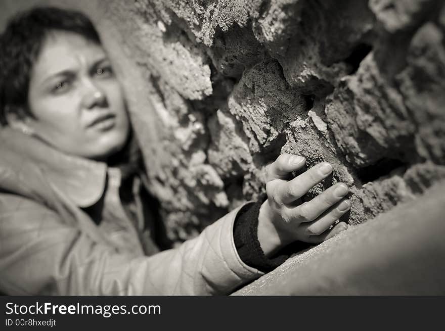 A view with a woman looking thoughtful in black and white tones. Shallow depth of field, focus on the hand.