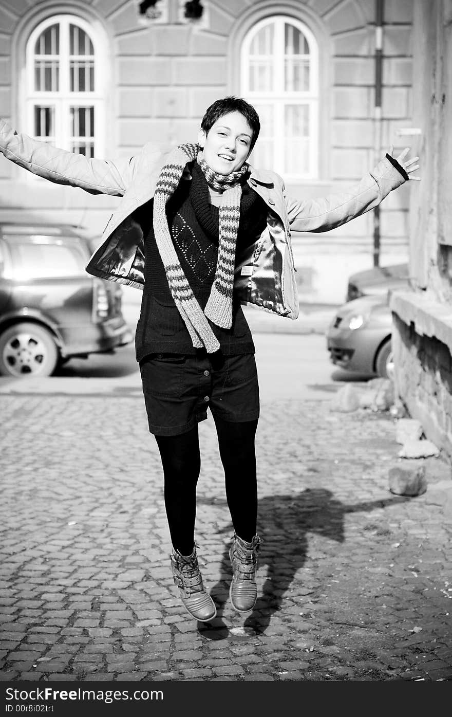 The young woman in a jump for joy on a public street.