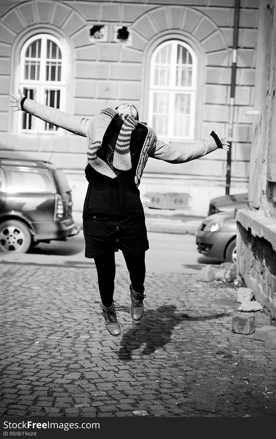 The young woman in a jump for joy on a public street.