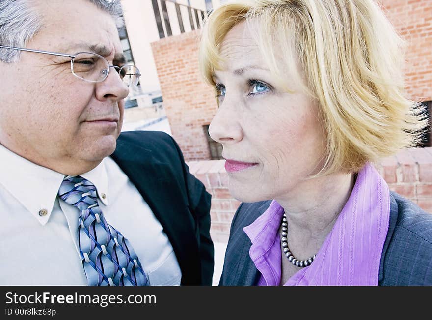 Executive man and woman on a downtown roof with ambiguous expressions. Executive man and woman on a downtown roof with ambiguous expressions