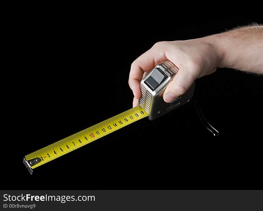 Measuring tape in hand. Isolated on a black background.